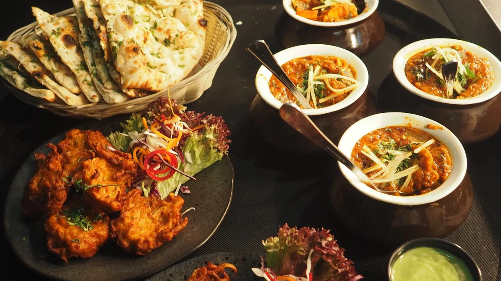 Restaurant spread of curries, pakora and naan ready for sharing.