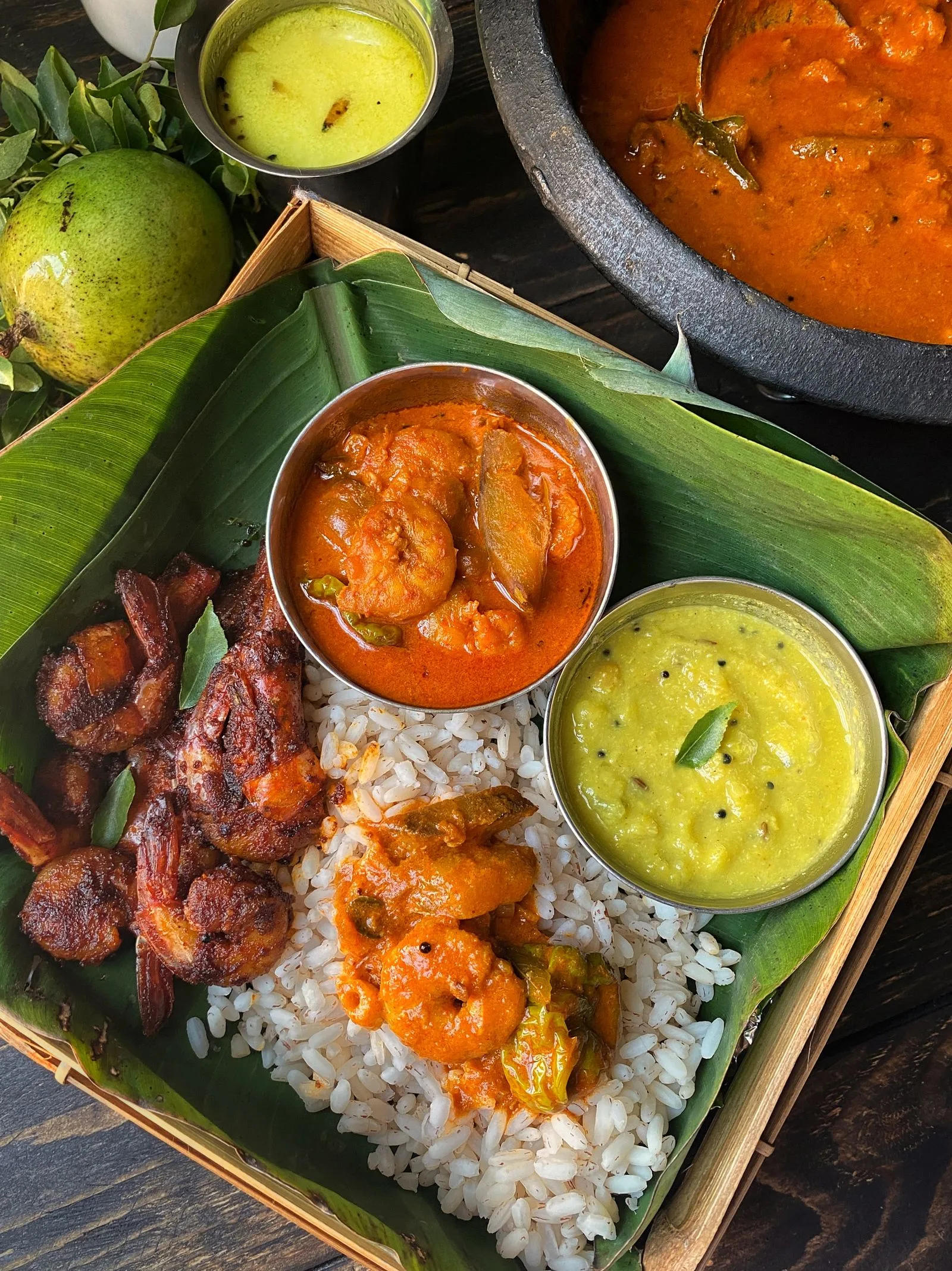 Rice with prawn curry, fried shrimp, dhal and sambols served on a banana leaf.