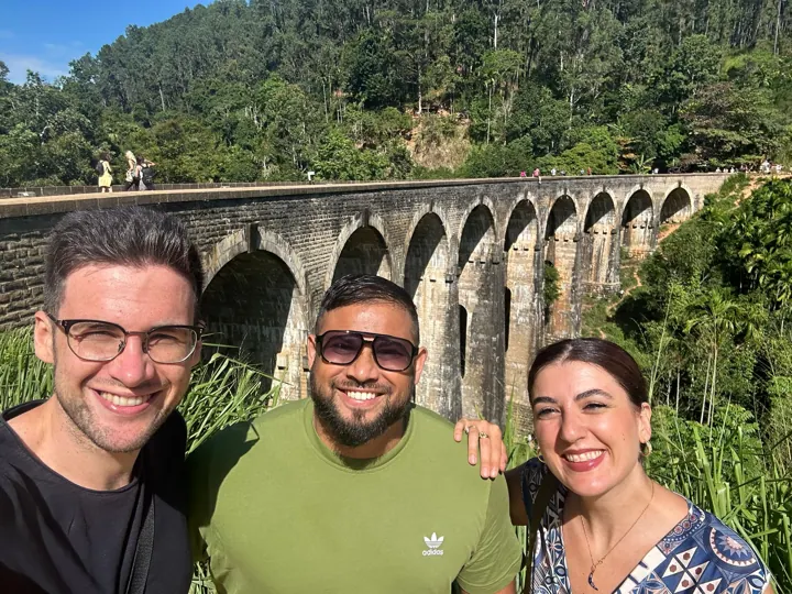Travellers beside a stone railway viaduct and green hills