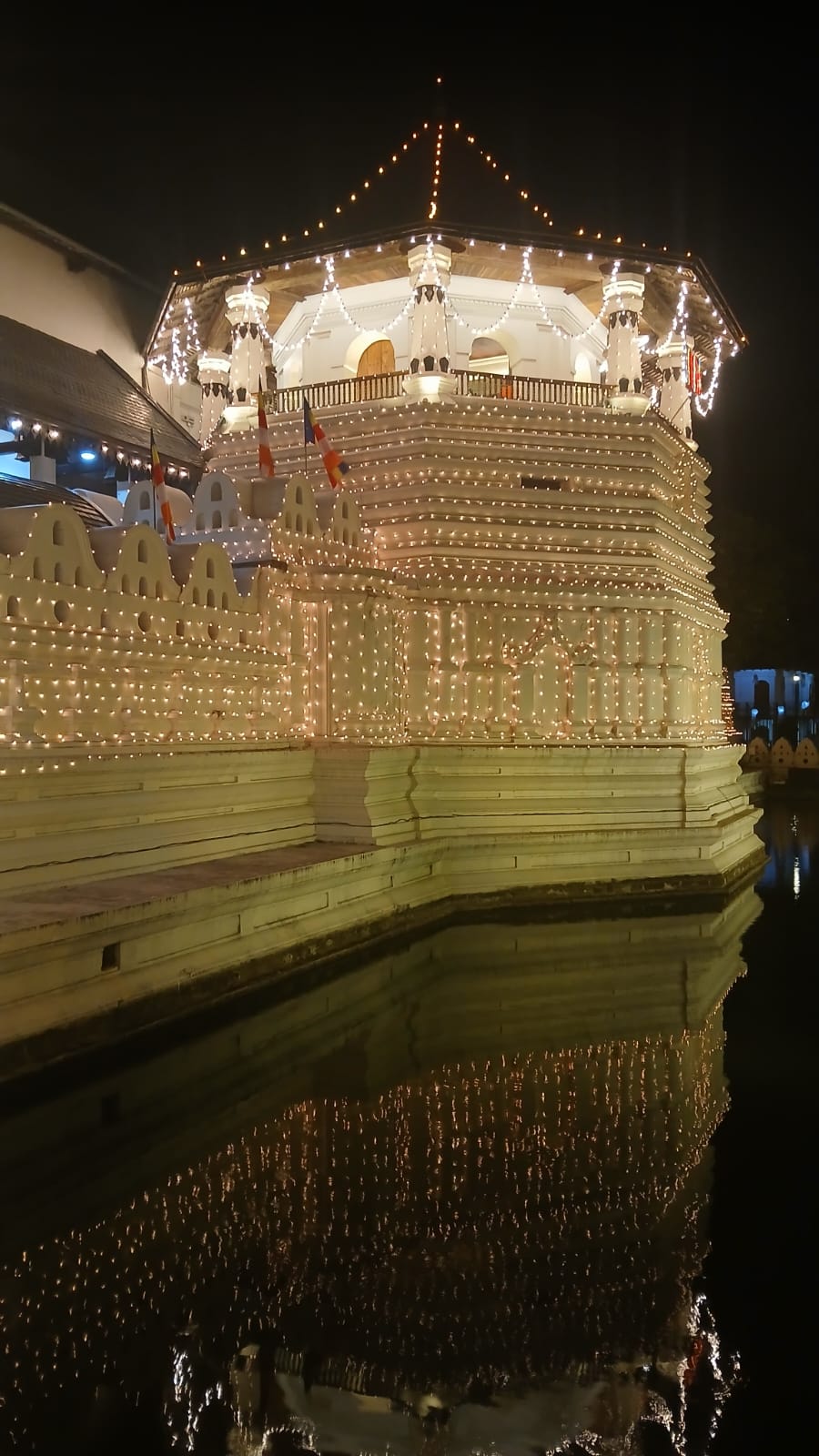 Lights on the temple’s octagonal pavilion reflected in the moat at night.