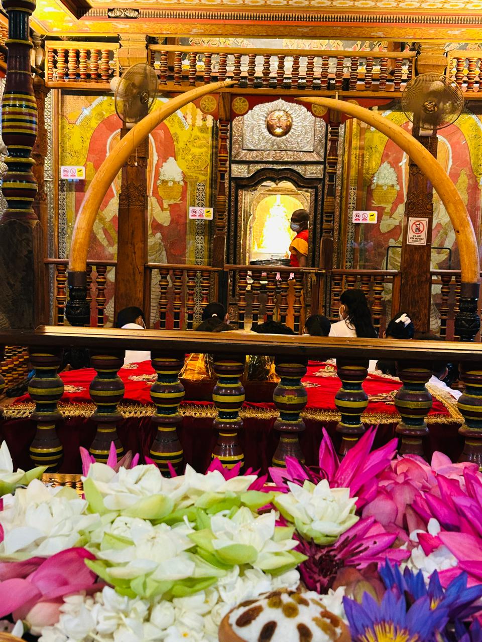 Devotees and flower offerings inside the richly decorated Temple of the Sacred Tooth Relic.