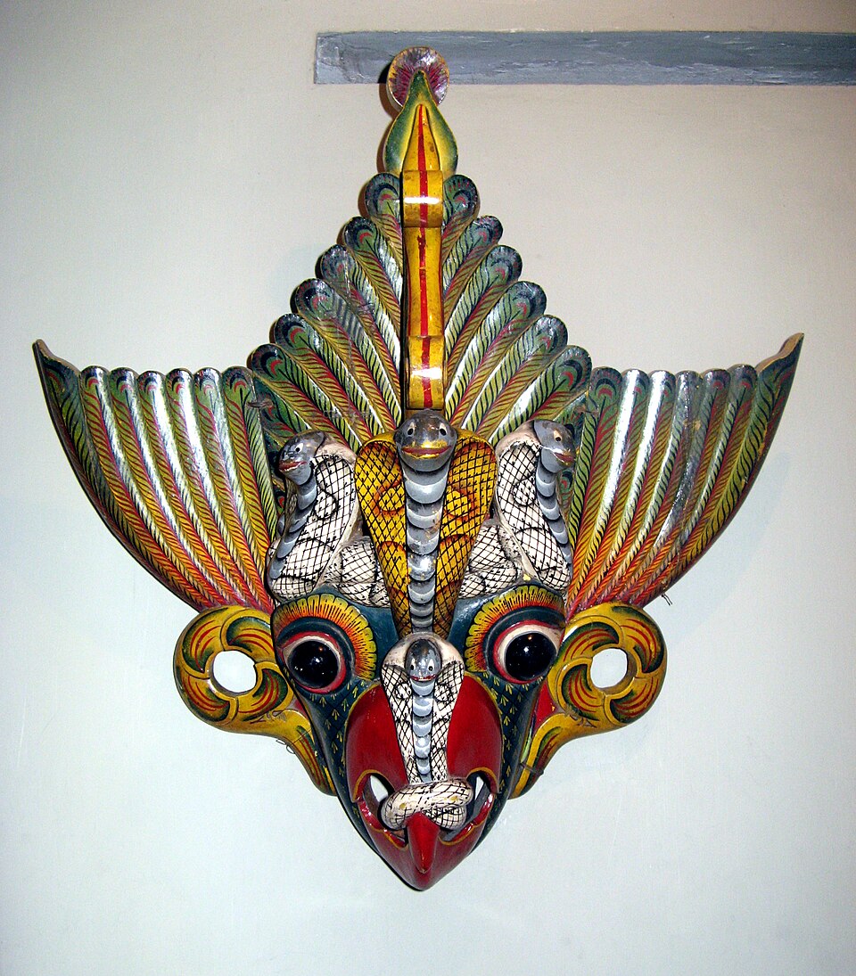 A brightly painted Garuda Raksha mask with a bird-like face and decorative snakes