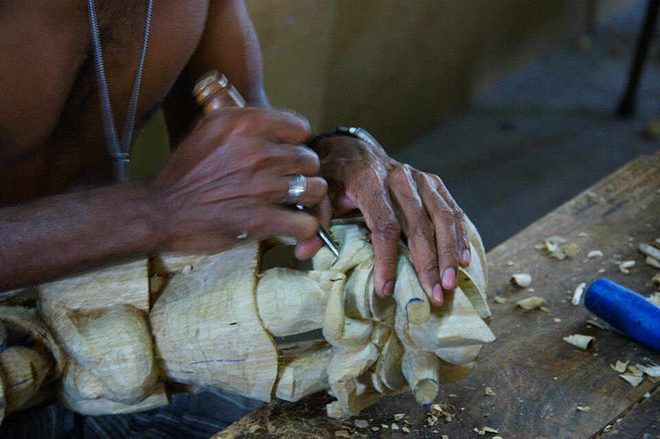 A craftsperson hand-carving the face of a wooden mask in Ambalangoda